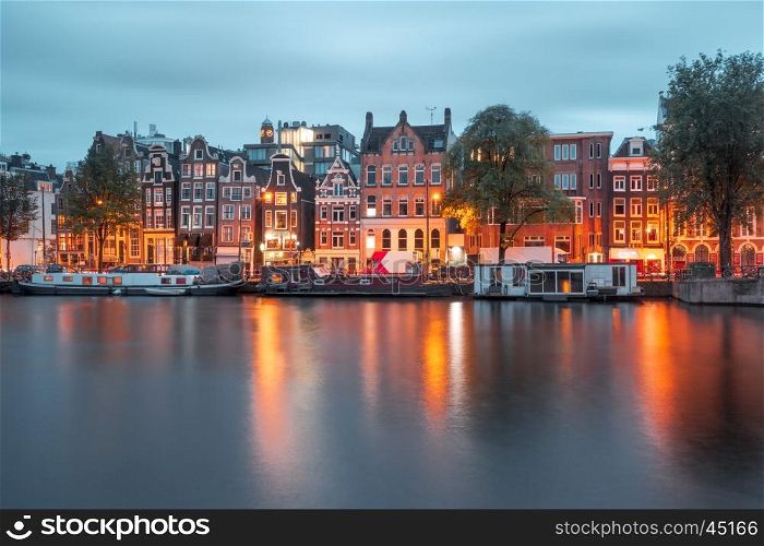 Amsterdam canal Amstel with typical dutch houses and boats during twilight blue hour, Holland, Netherlands.
