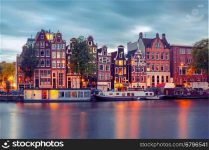 Amsterdam canal Amstel with typical dutch houses and boats during twilight blue hour, Holland, Netherlands. Used toning