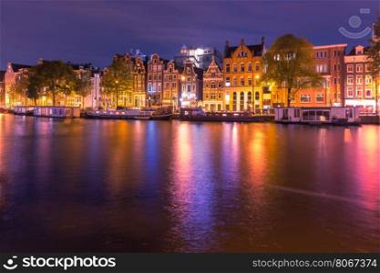 Amsterdam canal Amstel with typical dutch houses and houseboats with multi-colored reflections at night, Holland, Netherlands.