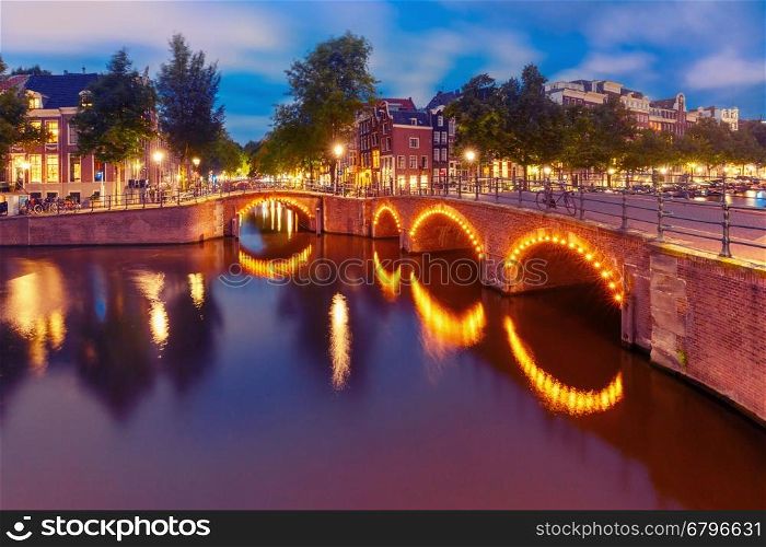 Amsterdam canal, bridge and typical houses, boats and bicycles during evening twilight blue hour, Holland, Netherlands. Used toning
