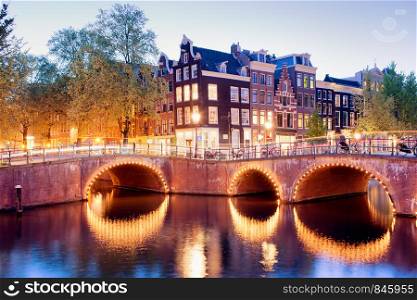 Amsterdam canal bridges illuminated at evening, Netherlands, North Holland province.