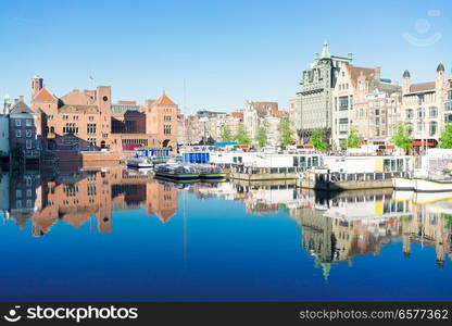 Amsterdam canal Damrak with typical dutch houses and boats at morning blue hour, Holland, Netherlands.. Houses of Amsterdam, Netherlands