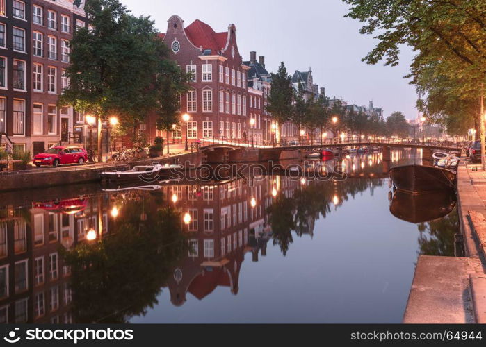 Amsterdam canal Kloveniersburgwal, Holland. Amsterdam canal Kloveniersburgwal with typical dutch houses, bridge and houseboats during morning blue hour, Holland, Netherlands.