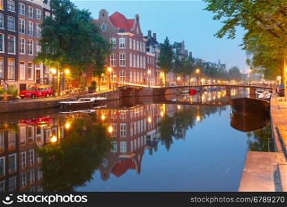 Amsterdam canal Kloveniersburgwal with typical dutch houses, bridge and houseboats during morning blue hour, Holland, Netherlands.