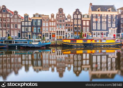 Amsterdam canal Singel with typical dutch houses and houseboats during morning blue hour, Holland, Netherlands.