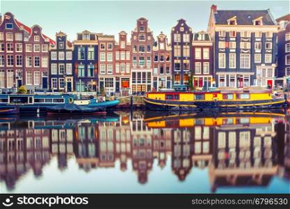 Amsterdam canal Singel with typical dutch houses and houseboats during morning blue hour, Holland, Netherlands. Used toning
