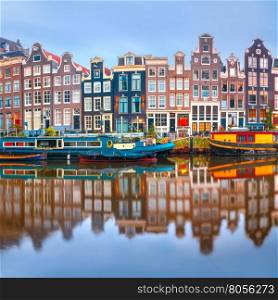 Amsterdam canal Singel with typical dutch houses and houseboats during morning blue hour, Holland, Netherlands.