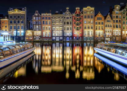 Amsterdam canal Singel with typical dutch houses and houseboats during night, Holland, Netherlands.. Traditional old buildings in Amsterdam, the Netherlands