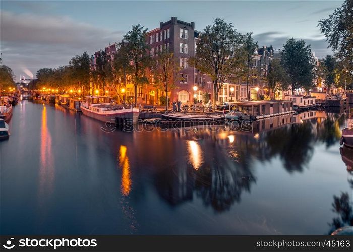 Amsterdam canals and typical houses, boats and bicycles during evening twilight blue hour, Holland, Netherlands.
