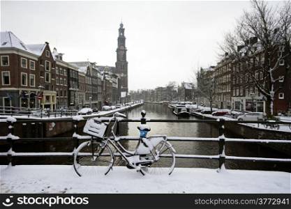 Amsterdam covered with snow with the Westerkerk in winter in the Netherlands