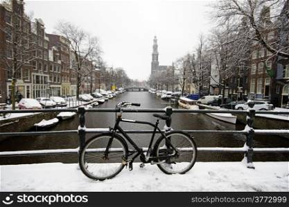 Amsterdam covered with snow with the Westerkerk in winter in the Netherlands