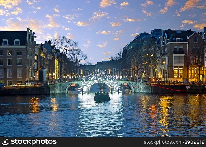 Amsterdam lights in the city center at the river Amstel in the Netherlands at sunset