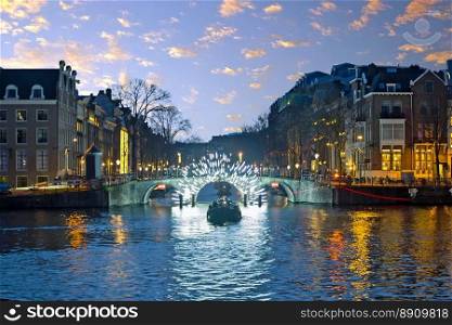 Amsterdam lights in the city center at the river Amstel in the Netherlands at sunset