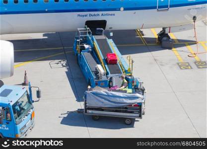 AMSTERDAM, NETHERLANDS - AUGUST 17, 2016: Loading luggage in airplane at Amsterdam Schiphol airport, Netherlands on August 17, 2016. Schiphol is the fourth biggest airport in Europe.