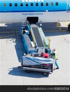 AMSTERDAM, NETHERLANDS - AUGUST 17, 2016: Loading luggage in airplane at Amsterdam Schiphol airport, Netherlands on August 17, 2016. Schiphol is the fourth biggest airport in Europe.