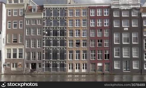 AMSTERDAM, NETHERLANDS - AUGUST 9, 2016: View of old Europa typical district with buildings in the city center on the river. Amsterdam is home to more than one hundred kilometres (60 miles) of canals