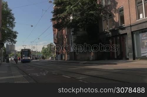 AMSTERDAM, NETHERLANDS - AUGUST 9, 2016: View of tram number 2 moving along the street from station in the city at the day and then bikers, more than 5 million international visitors annually