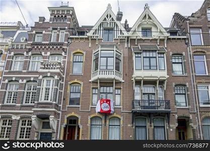 Amsterdam, Netherlands - May 16, 2019: Dutch facades with the Ajax flag honoring the national championship from Ajax in Amsterdam the Netherlands