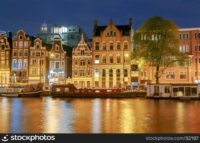 Amsterdam. Night view of the houses along the canal.. Facades of traditional Dutch houses on the canal in the night light. Amsterdam. Netherlands.
