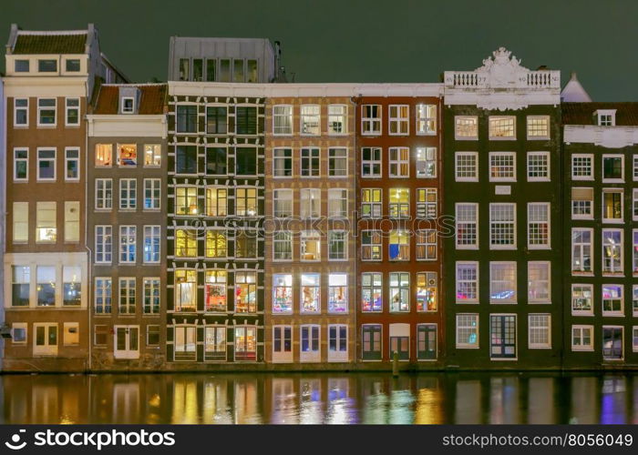 Amsterdam. Night view of the houses along the canal.. Facades of traditional Dutch houses on the canal in the night light. Amsterdam. Netherlands.