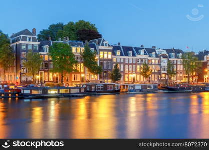 Amsterdam. Night view of the houses along the canal.. Facades of traditional Dutch houses on the canal in the night light. Amsterdam. Netherlands.