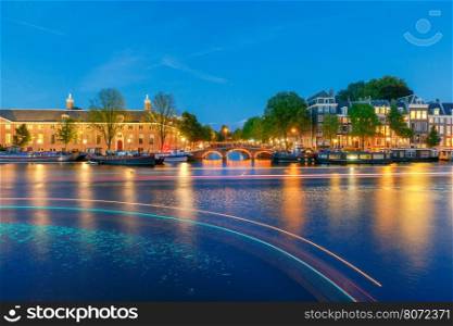 Amsterdam. Night view of the houses along the canal.. Facades of traditional Dutch houses on the canal in the night light. Amsterdam. Netherlands.
