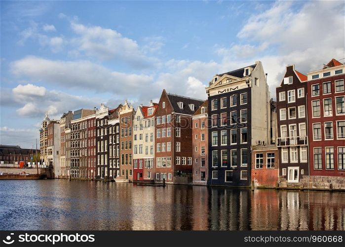Amsterdam Old Town at sunset in Netherlands, terraced Dutch style historic houses with reflections on water.