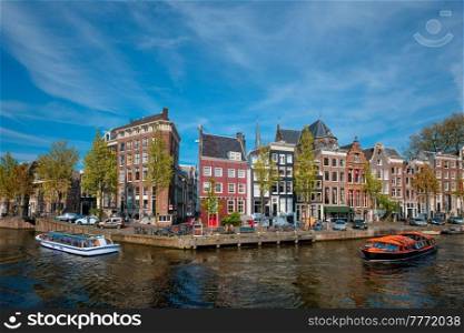 Amsterdam view - canal with tourist boat, bridge and old houses. Amsterdam, Netherlands. Amsterdam view - canal with boad, bridge and old houses