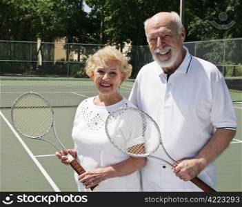 An active, happy senior couple on the tennis courts.