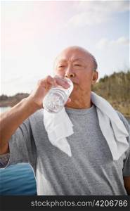 An active senior asian man drinking water after exercise