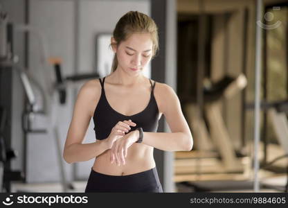 An active woman is using smart watch in fitness gym. Fitness and technology concept .. Active woman is using smart watch in fitness gym. Fitness and technology concept .