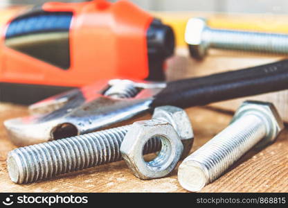 An adjustable spanner lies near the bolts and nuts of the washer against the background of wooden boards. The concept of tools and repair work.. An adjustable spanner lies near the bolts and nuts of the washer against the background of wooden boards.