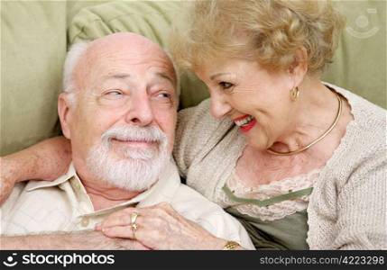 An adorable senior couple laughing together at home. It&rsquo;s obvious they still have chemistry together.