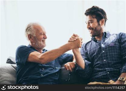 An adult son and senior father indoors at home making fist bump.