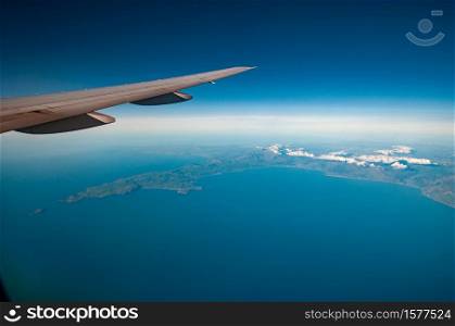 An aerial view across the northern end of Cardigan Bay towards Anglesey and Snowdonia (which is covered in cloud) - view includes wingtip of aircraft. Aerial view of North Cardigan Bay, Wales