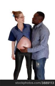 An African American man and his Caucasian pregnant wife standingisolated for white background and smiling to each other.