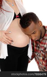 An African American man holding his ear on his wife&rsquo;s baby belly,listening for his heartbeat, isolated for white background.
