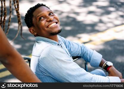 An african american man in a wheelchair enjoying a walk outdoors with his girlfriend.