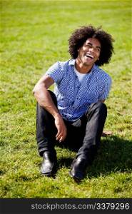 An African American sitting on grass with a natural laugh