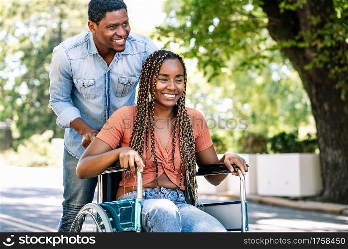 An african american woman in a wheelchair enjoying a walk with her boyfriend.