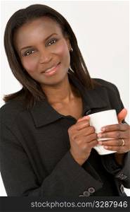 An African American woman warming her hands around a warm drink in a white mug