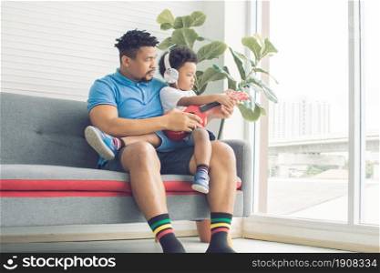 An african black father teaching and playing ukulele with his little son in living room at home. Education and Family concept.