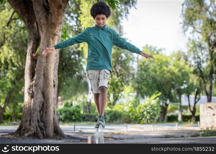 An African curly haired boy stood with his arms outstretched on the iron railing.