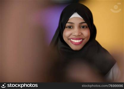 an african muslim woman with a beautiful smile wearing a hijab poses in the studio
