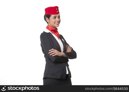 An air hostess with arms crossed looking away against white background