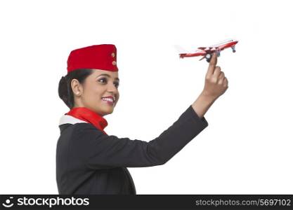 An airhostess holding toy airplane isolated over white background