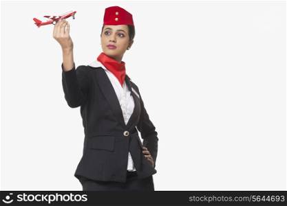 An airhostess looking at toy airplane isolated over white background