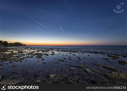 an amazing tranquil scene of a rocky shore before sunrise. Blue hour