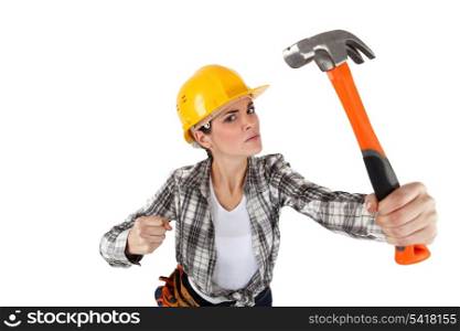 An angry female construction worker with a hammer.