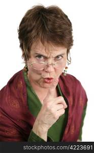 An angry middle aged librarian putting her finger to her lips to tell you to be quiet. Isolated on white